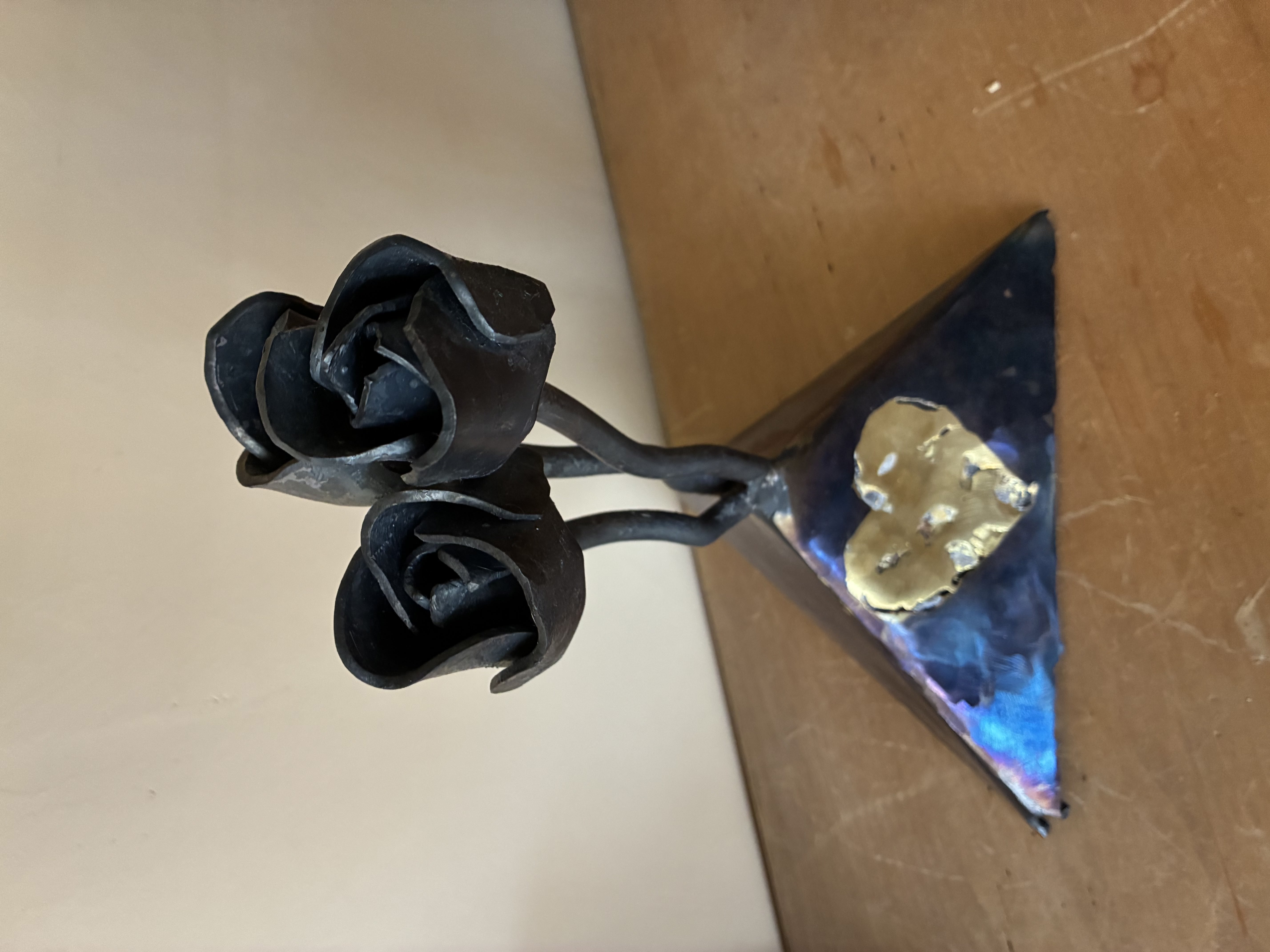 three metal flowers connected to a base with a brass heart embedded in it